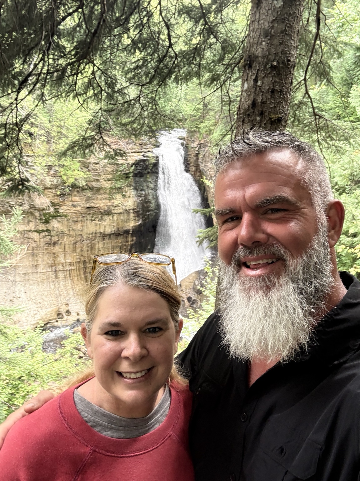 Luke and Megan smiling together beside a waterfall